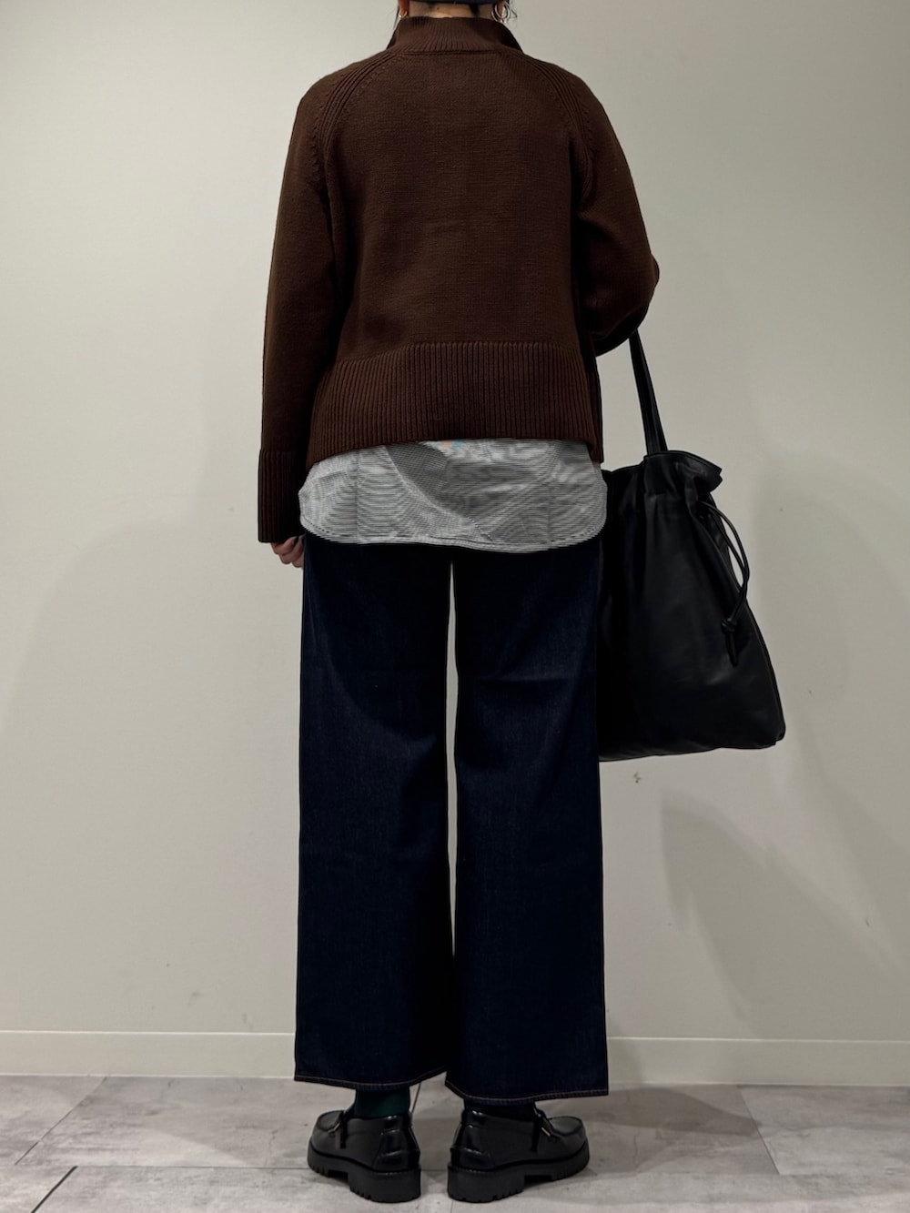 ブラック系のトートバッグ、ブルー系のデニムパンツ、ブラック系のローファーを着用したレディースの冬コーディネートの3枚目の写真