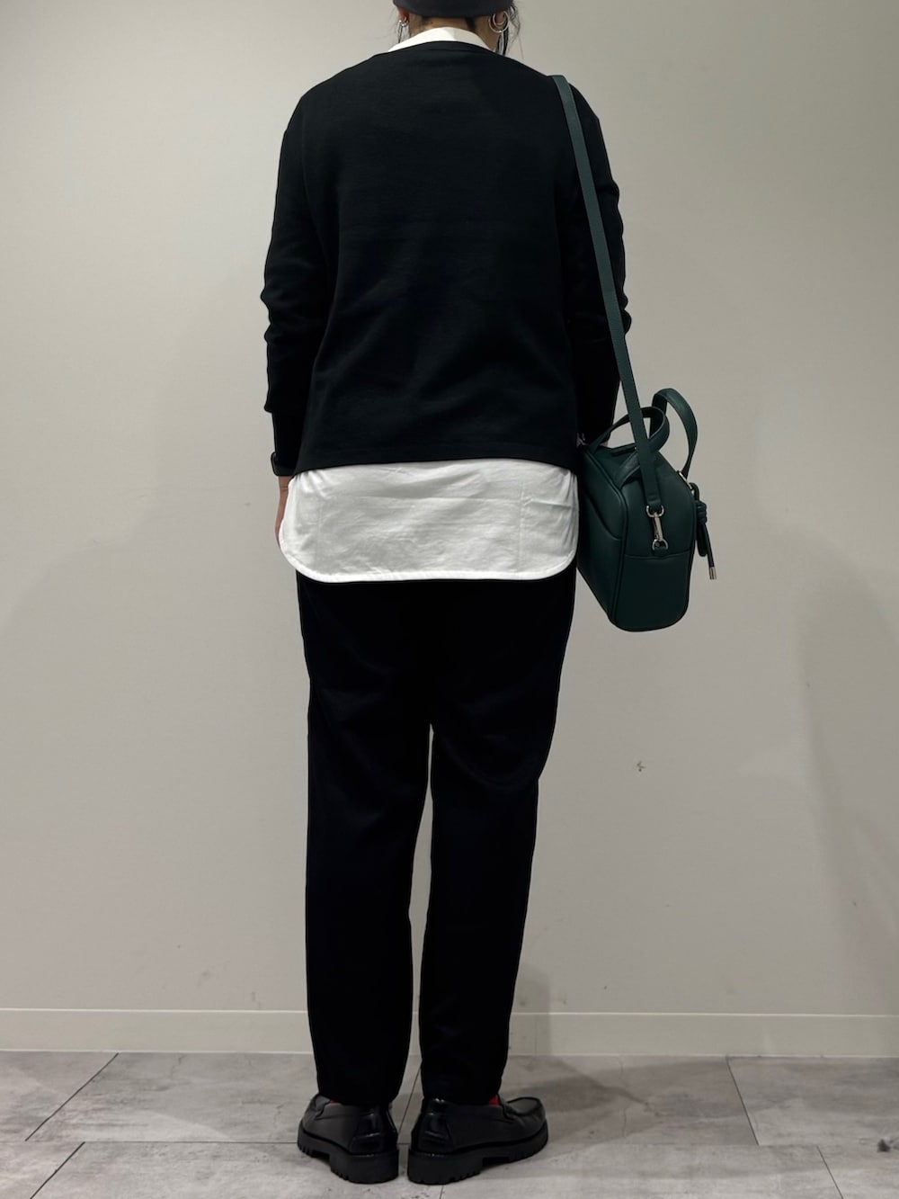 グリーン系のボストンバッグ、ブラック系のニット/セーター、ホワイト系のTシャツ/カットソーを着用したレディースの冬コーディネートの3枚目の写真