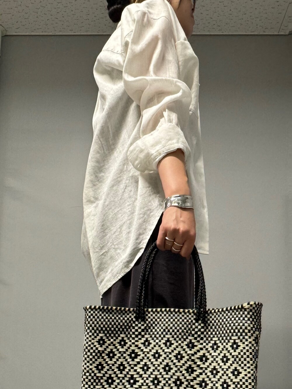 グレー系のワンピース、ホワイト系のシャツ/ブラウス、ブラック系のサンダルを着用したレディースの夏コーディネートの2枚目の写真