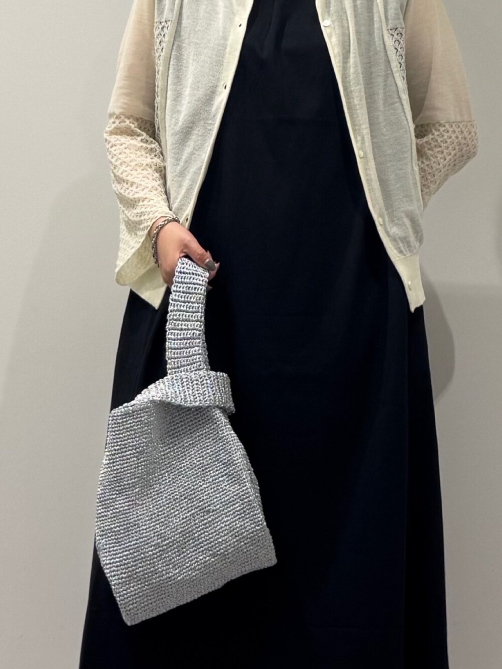 シルバー系のかごバッグ、ブラック系のワンピース、ホワイト系のカーディガン/ボレロを着用したレディースの秋コーディネートの9枚目の写真