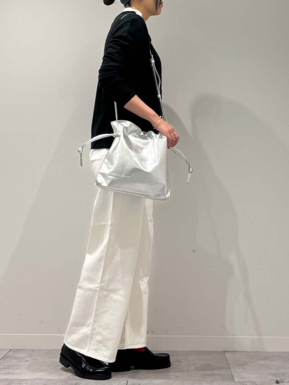 シルバー系のショルダーバッグ、ホワイト系のデニムパンツ、ブラック系のローファーを着用したレディースの冬コーディネートの2枚目の写真