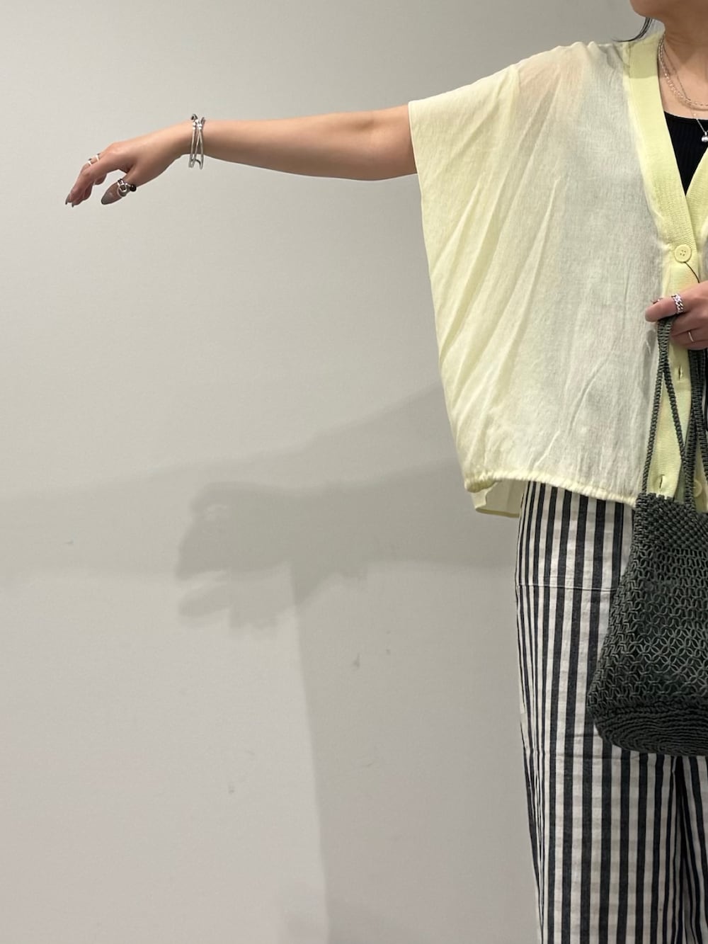 グリーン系のかごバッグ、ブラック系のその他パンツ、ブラック系のサンダルを着用したレディースの春コーディネートの6枚目の写真