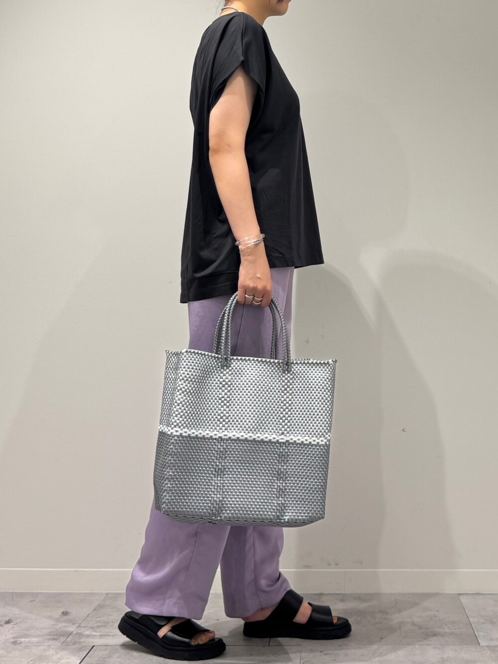 グレー系のTシャツ/カットソー、シルバー系のかごバッグ、ブラック系のサンダルを着用したレディースの夏コーディネートの2枚目の写真