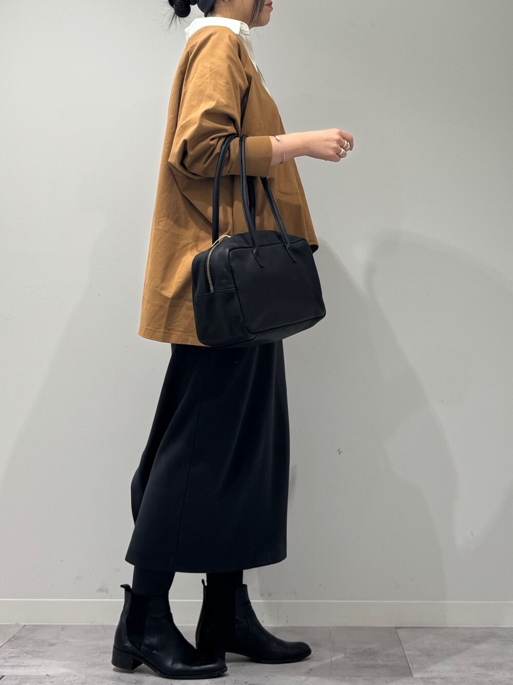 ブラック系のボストンバッグ、ベージュ系のTシャツ/カットソー、シルバー系のネックレスを着用したレディースの冬コーディネートの2枚目の写真