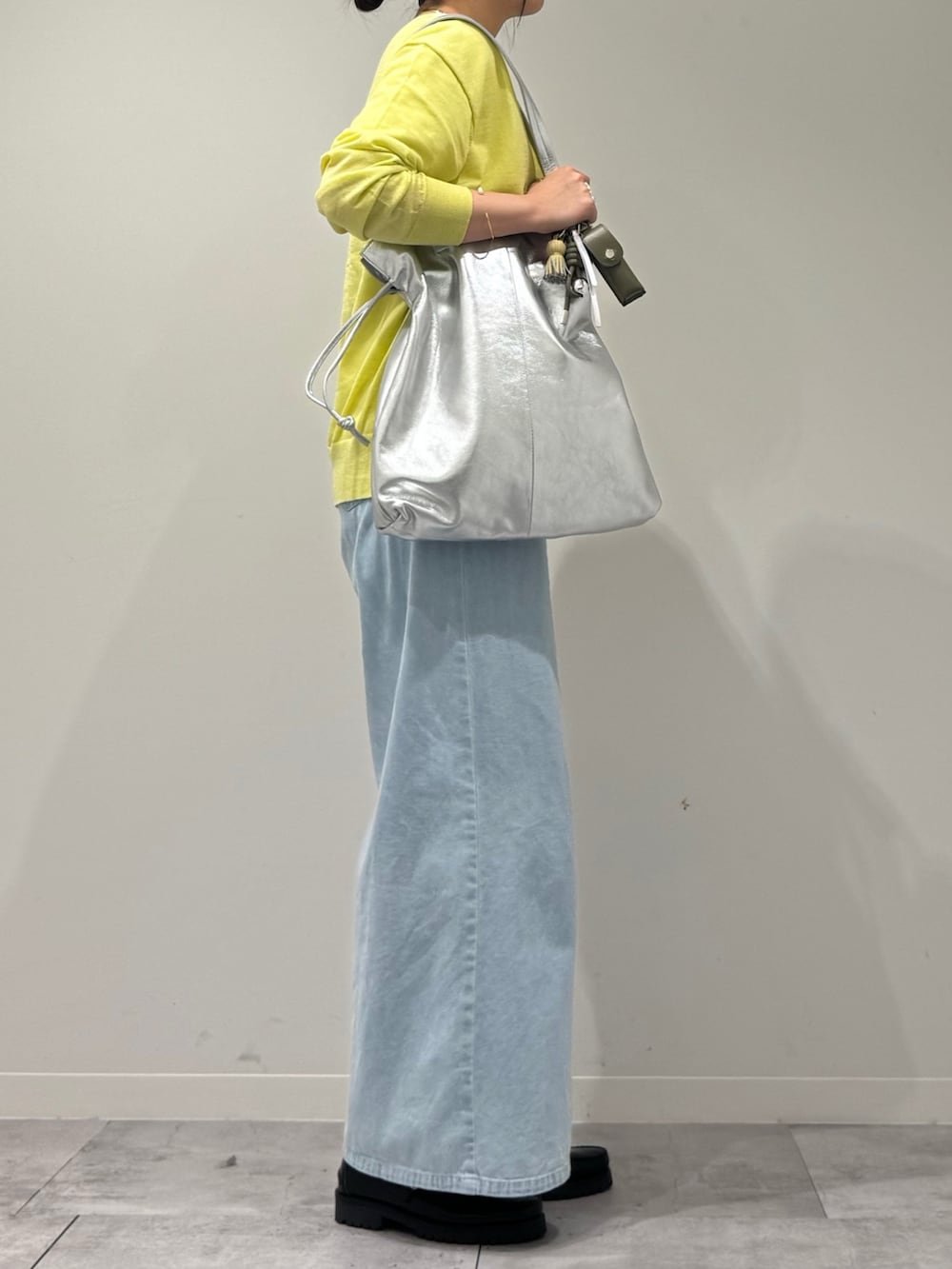 シルバー系のトートバッグ、ブラック系のローファー、ブルー系のデニムパンツを着用したレディースの春コーディネートの2枚目の写真
