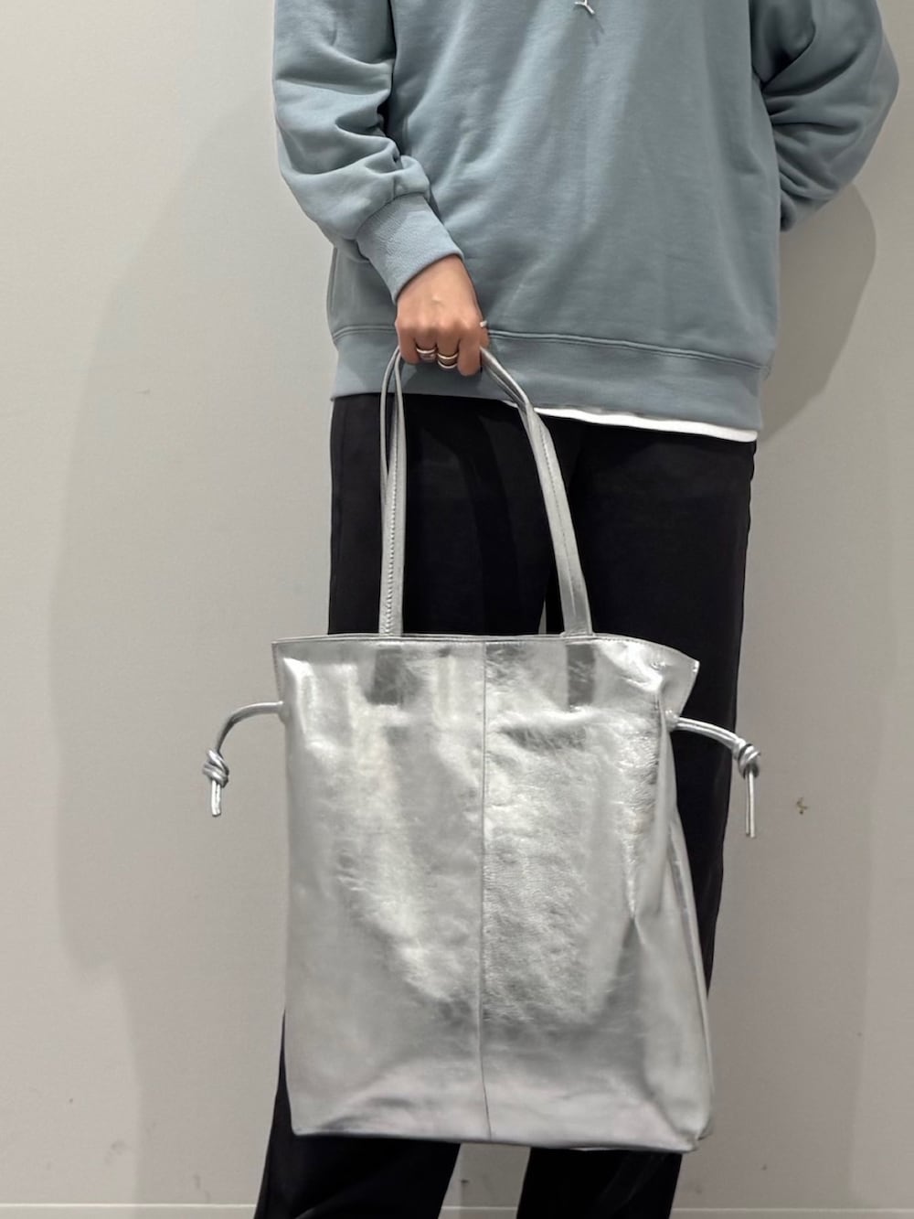 シルバー系のトートバッグ、ブルー系のスウェット、ホワイト系のTシャツ/カットソーを着用したレディースの冬コーディネートの8枚目の写真