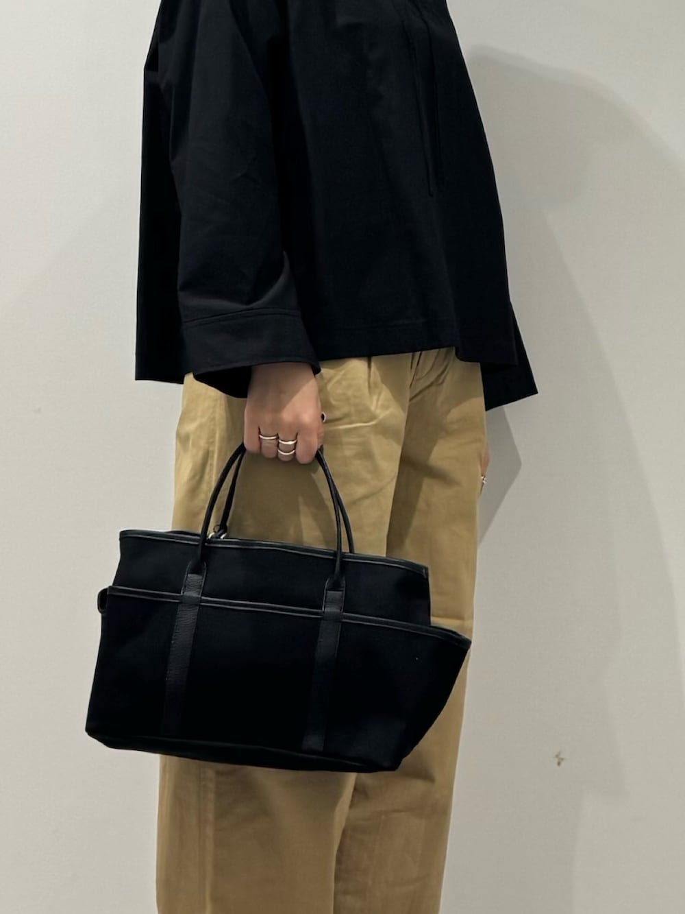 ブラック系のスニーカー、ベージュ系のチノパンツ、ブラック系のシャツ/ブラウスを着用したレディースの秋コーディネートの8枚目の写真