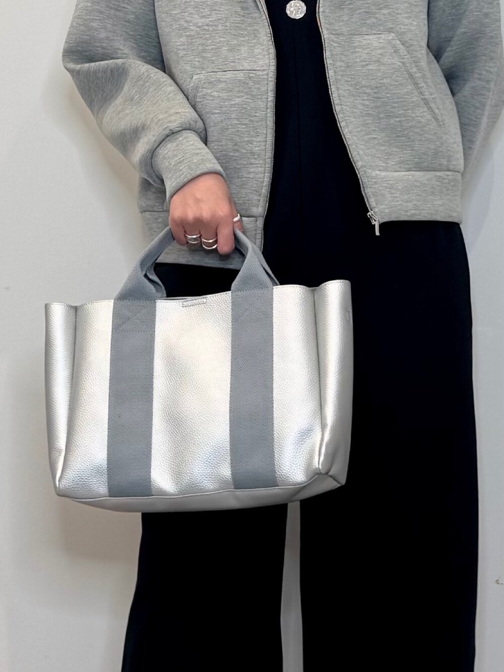 シルバー系のトートバッグ、ブラック系のサロペット/オーバーオール、グレー系のパーカーを着用したレディースの冬コーディネートの7枚目の写真