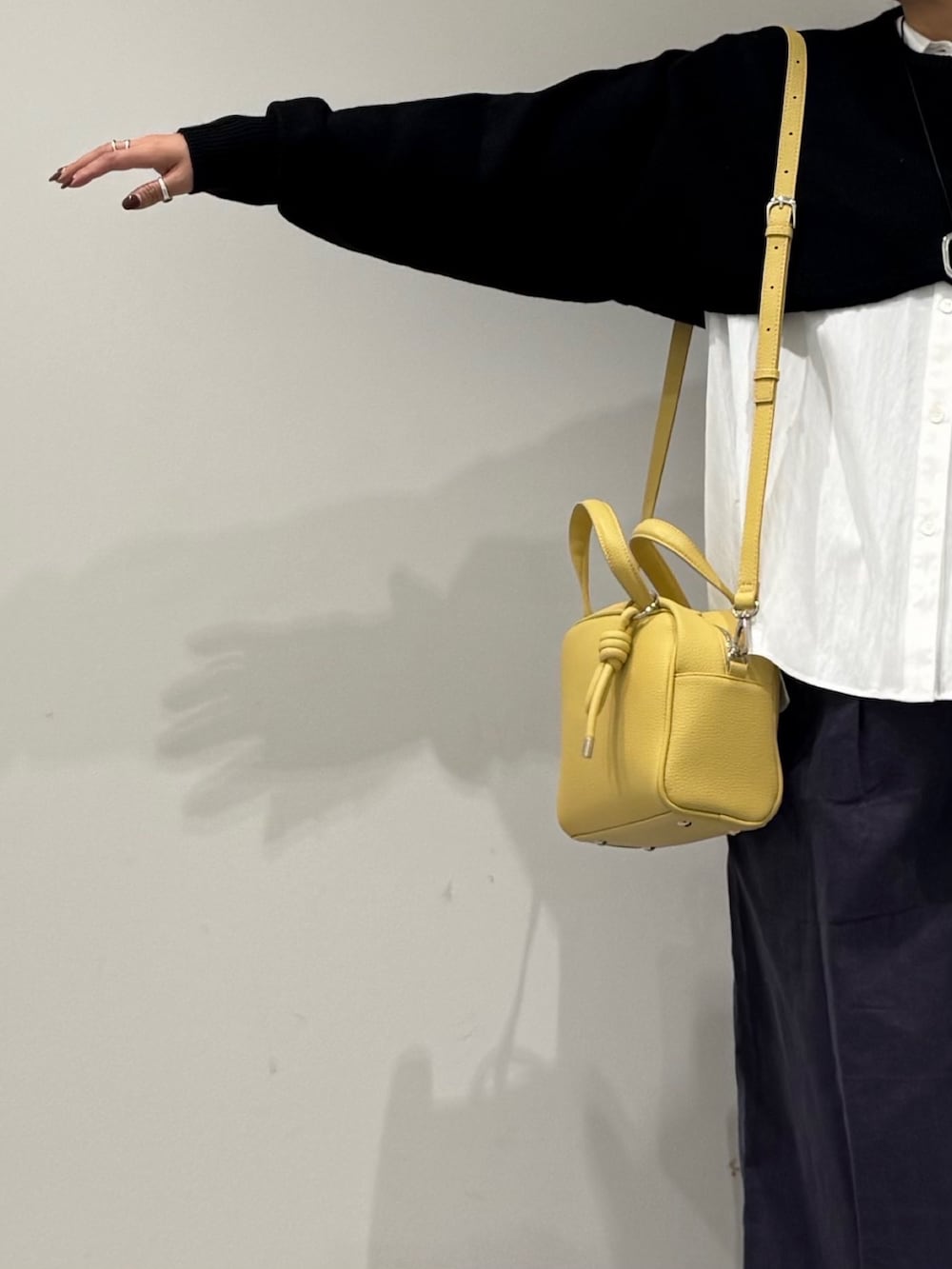 イエロー系のボストンバッグ、ブラック系のローファー、ホワイト系のシャツ/ブラウスを着用したレディースの冬コーディネートの6枚目の写真