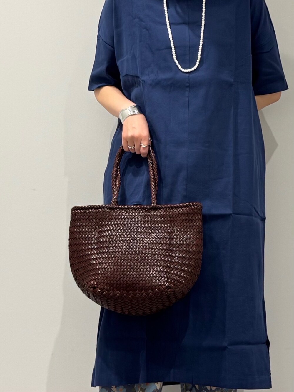 ブラウン系のトートバッグ、ブルー系のその他パンツ、ブラック系のサンダルを着用したレディースの春コーディネートの8枚目の写真