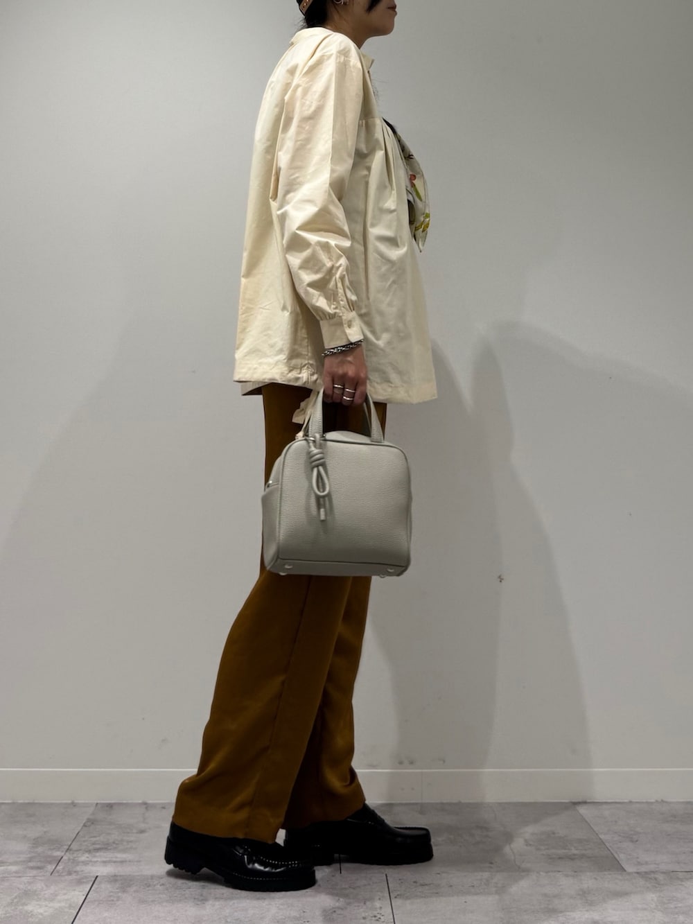 グレー系のボストンバッグ、ホワイト系のシャツ/ブラウス、ブラウン系のその他パンツを着用したレディースの秋コーディネートの2枚目の写真