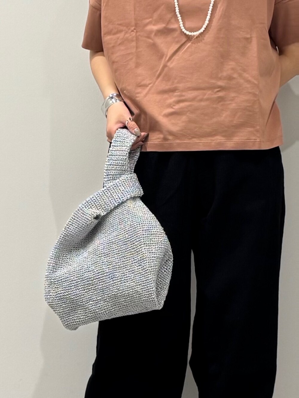 シルバー系のかごバッグ、ブラック系のサンダル、ゴールド系のネックレスを着用したレディースの春コーディネートの8枚目の写真