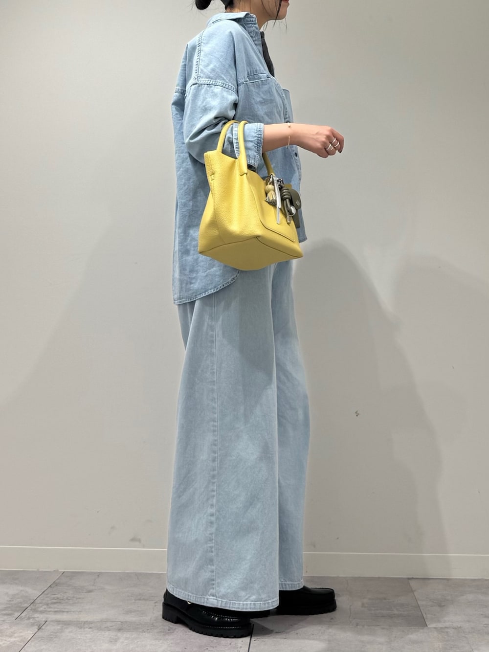 イエロー系のショルダーバッグ、ブルー系のデニムパンツ、ブラック系のローファーを着用したレディースの春コーディネートの2枚目の写真