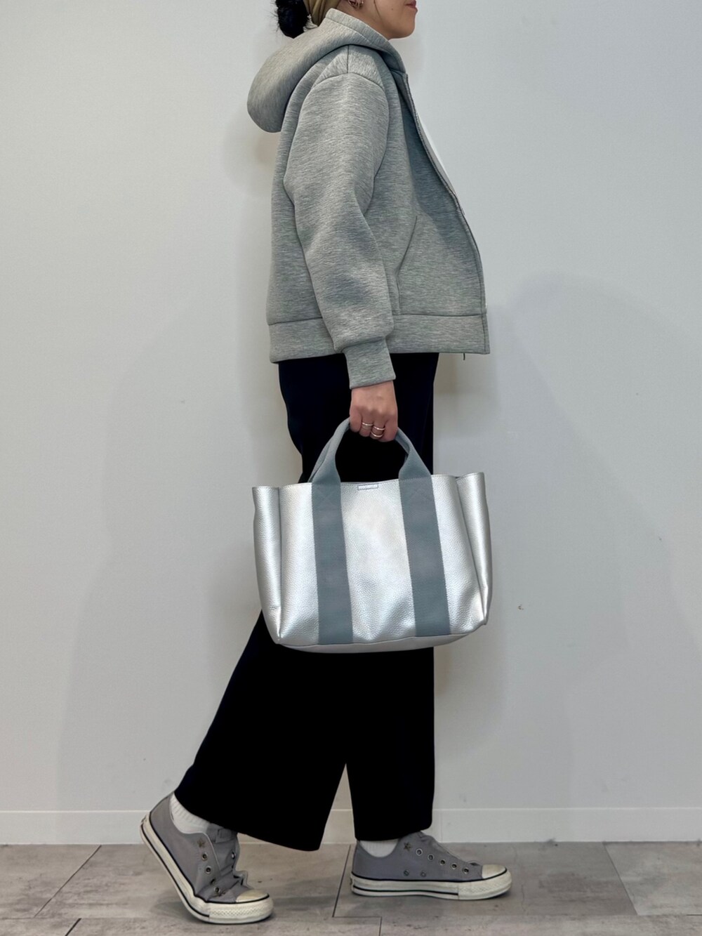 シルバー系のトートバッグ、ブラック系のサロペット/オーバーオール、グレー系のパーカーを着用したレディースの冬コーディネートの2枚目の写真