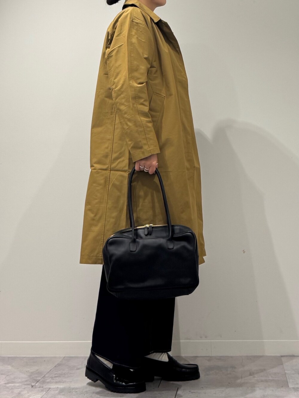 ブラック系のボストンバッグ、ベージュ系のダウンジャケット/コート、ブルー系のデニムパンツを着用したレディースの冬コーディネートの3枚目の写真