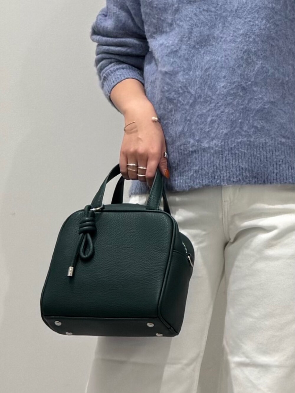 グリーン系のボストンバッグ、ホワイト系のデニムパンツ、ブラック系のローファーを着用したレディースの冬コーディネートの7枚目の写真