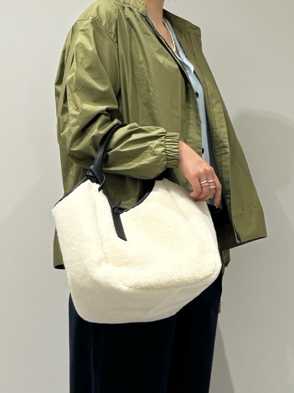 ホワイト系のトートバッグ、ブルー系のチノパンツ、グリーン系のブルゾンを着用したレディースの秋コーディネートの7枚目の写真