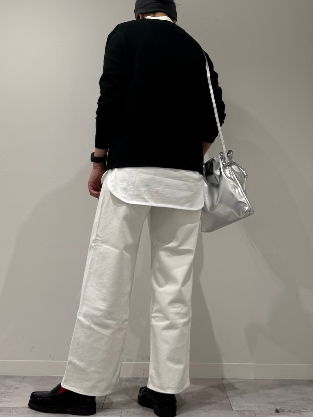 シルバー系のショルダーバッグ、ホワイト系のデニムパンツ、ブラック系のローファーを着用したレディースの冬コーディネートの4枚目の写真