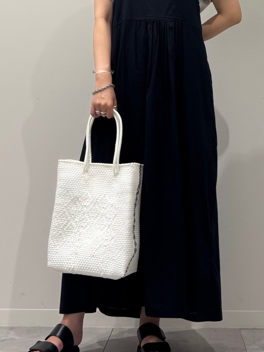 ブラック系のワンピース、ホワイト系のかごバッグ、ブラック系のサンダルを着用したレディースの夏コーディネートの7枚目の写真