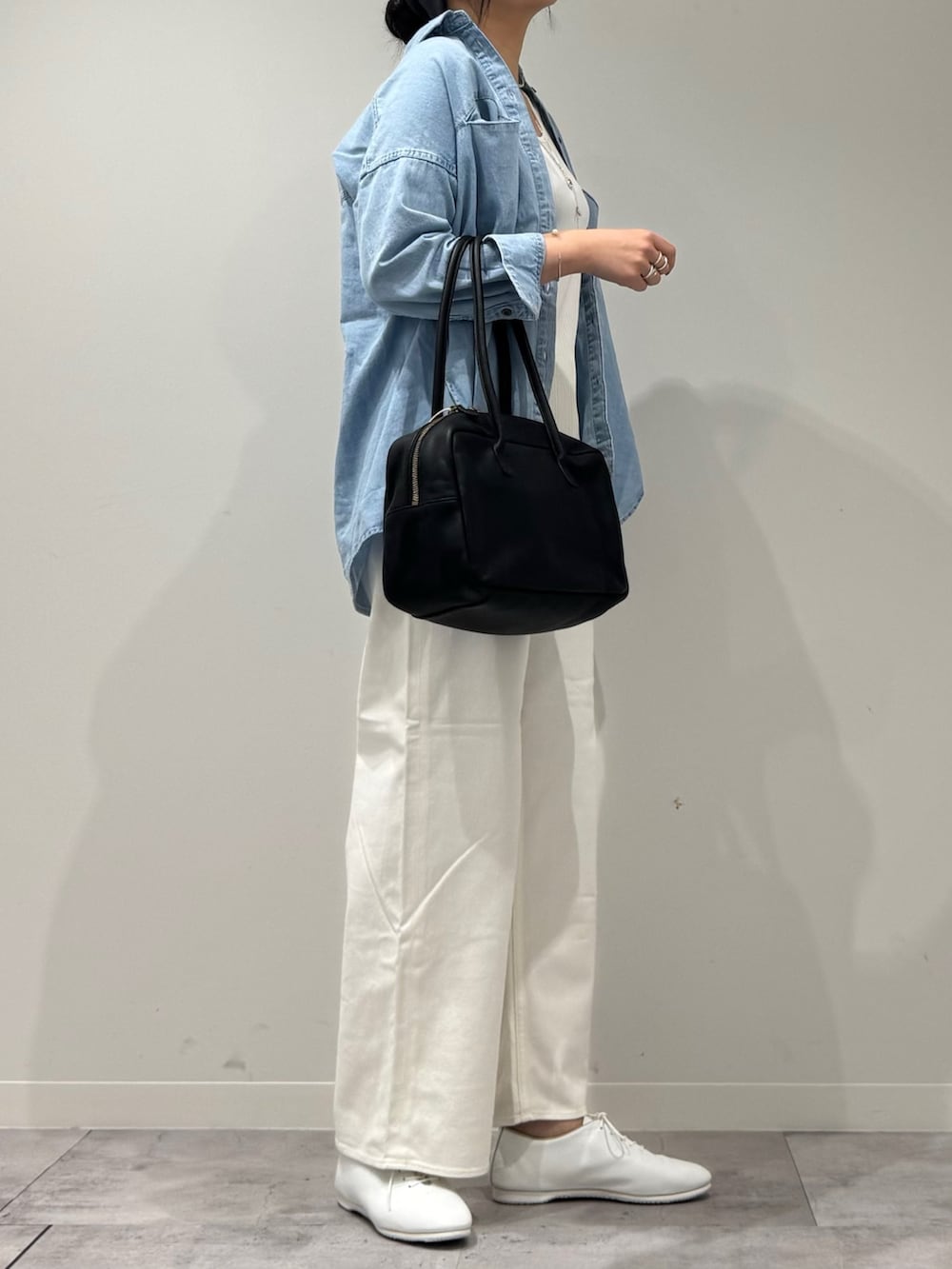 ブラック系のボストンバッグ、ホワイト系のデニムパンツ、ブルー系のシャツ/ブラウスを着用したレディースの春コーディネートの2枚目の写真