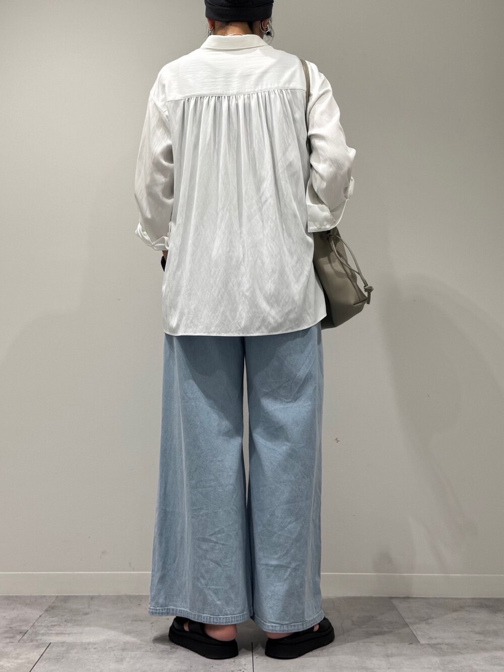 ベージュ系のショルダーバッグ、ブルー系のデニムパンツ、ブラック系のサンダルを着用したレディースの秋コーディネートの4枚目の写真