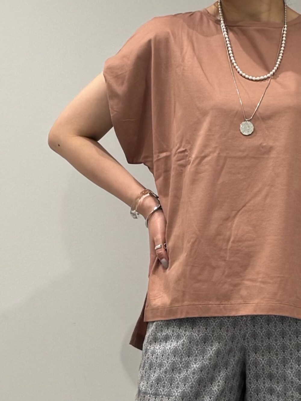 ピンク系のTシャツ/カットソー、シルバー系のかごバッグ、ベージュ系のその他パンツを着用したレディースの夏コーディネートの7枚目の写真