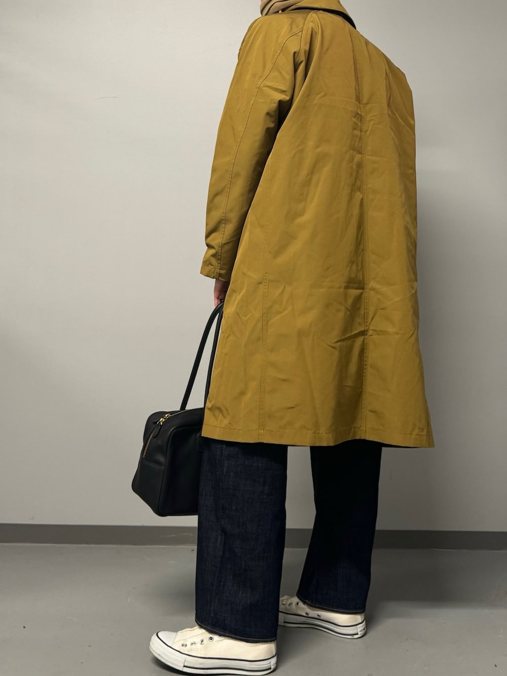 ベージュ系のダウンジャケット/コート、ブラック系のボストンバッグ、ブルー系のデニムパンツを着用したレディースの秋コーディネートの3枚目の写真