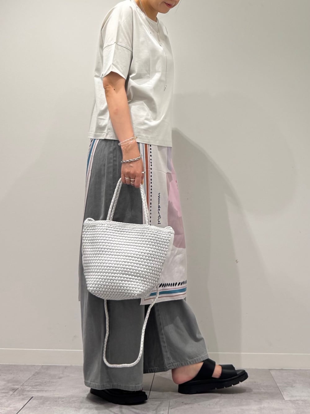 ホワイト系のトートバッグ、ブラック系のサンダル、グレー系のデニムパンツを着用したレディースの春コーディネートの2枚目の写真