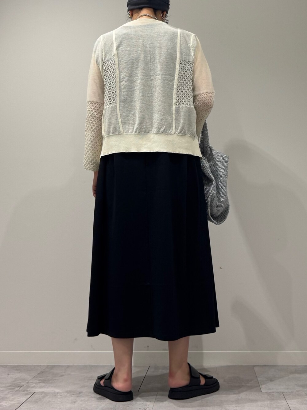 シルバー系のかごバッグ、ブラック系のワンピース、ホワイト系のカーディガン/ボレロを着用したレディースの秋コーディネートの4枚目の写真