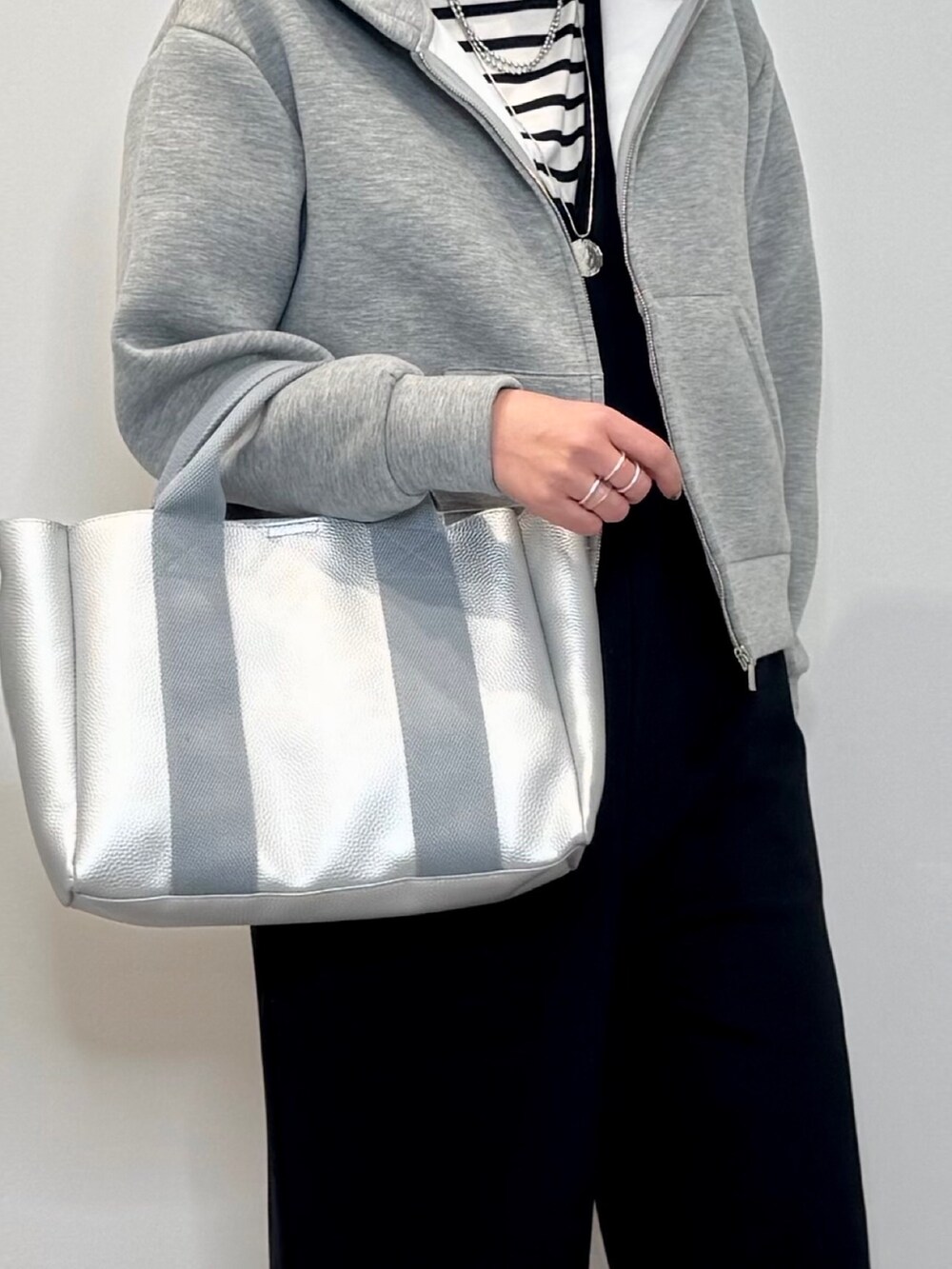 シルバー系のトートバッグ、ブラック系のサロペット/オーバーオール、グレー系のパーカーを着用したレディースの冬コーディネートの8枚目の写真