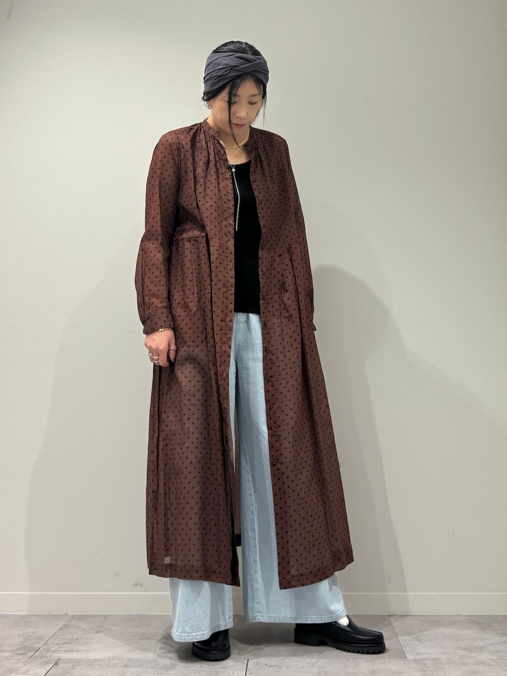 ブラウン系のワンピース、ブルー系のデニムパンツ、ブラック系のローファーを着用したレディースの春コーディネートの2枚目の写真