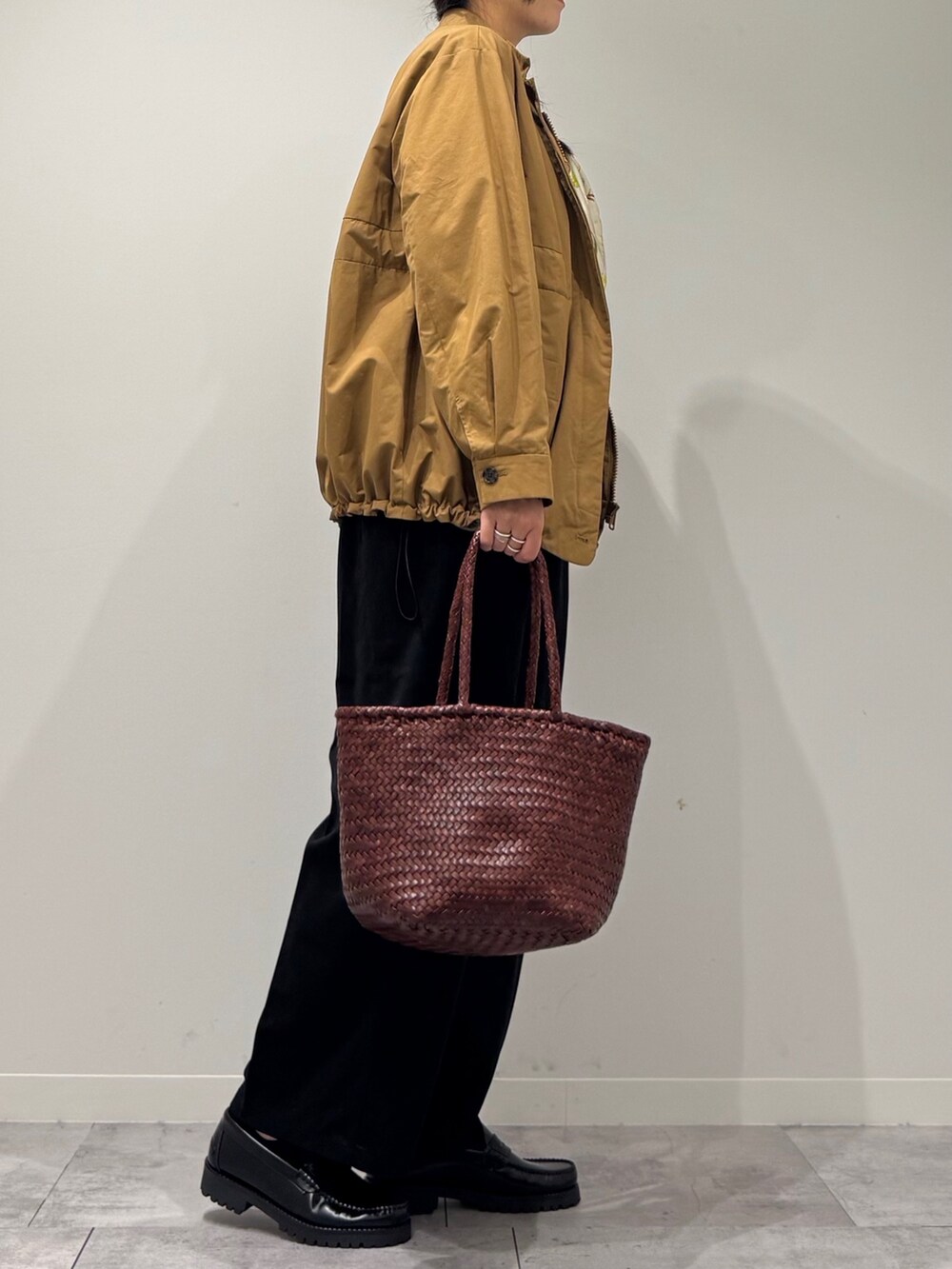 ブラウン系のトートバッグ、ブラック系のサロペット/オーバーオール、ブラック系のローファーを着用したレディースの秋コーディネートの2枚目の写真