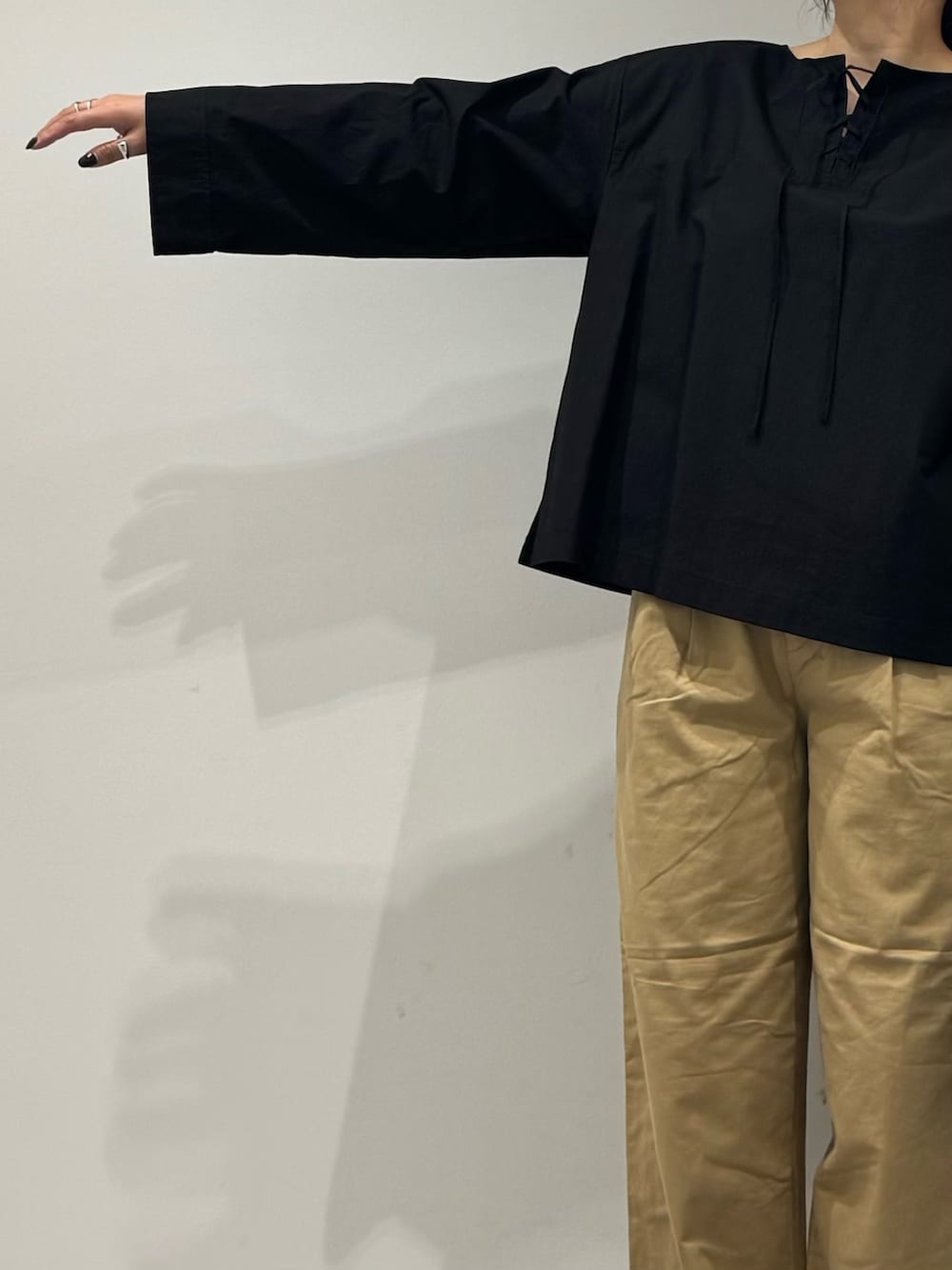 ブラック系のスニーカー、ベージュ系のチノパンツ、ブラック系のシャツ/ブラウスを着用したレディースの秋コーディネートの5枚目の写真
