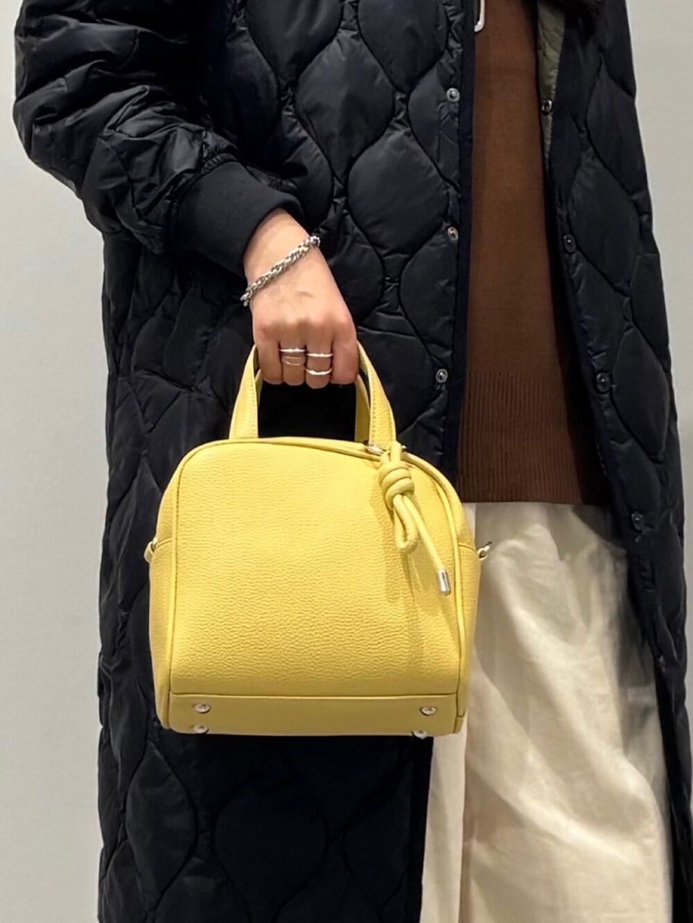 イエロー系のボストンバッグ、ブラウン系のベスト、ホワイト系のその他パンツを着用したレディースの秋コーディネートの7枚目の写真