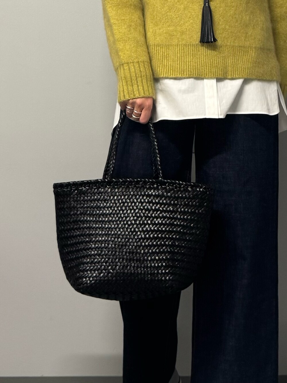 イエロー系のニット/セーター、ホワイト系のシャツ/ブラウス、ブルー系のデニムパンツを着用したレディースの冬コーディネートの4枚目の写真