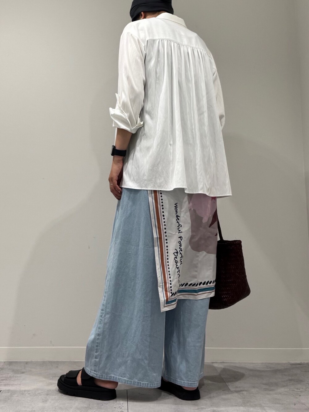 ブラウン系のトートバッグ、ブルー系のデニムパンツ、ブラック系のサンダルを着用したレディースの秋コーディネートの4枚目の写真