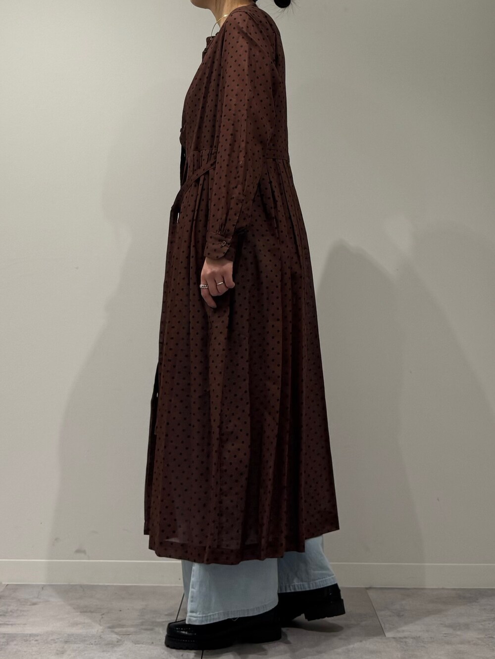 ブラウン系のワンピース、ブルー系のデニムパンツ、ブラック系のローファーを着用したレディースの春コーディネートの6枚目の写真