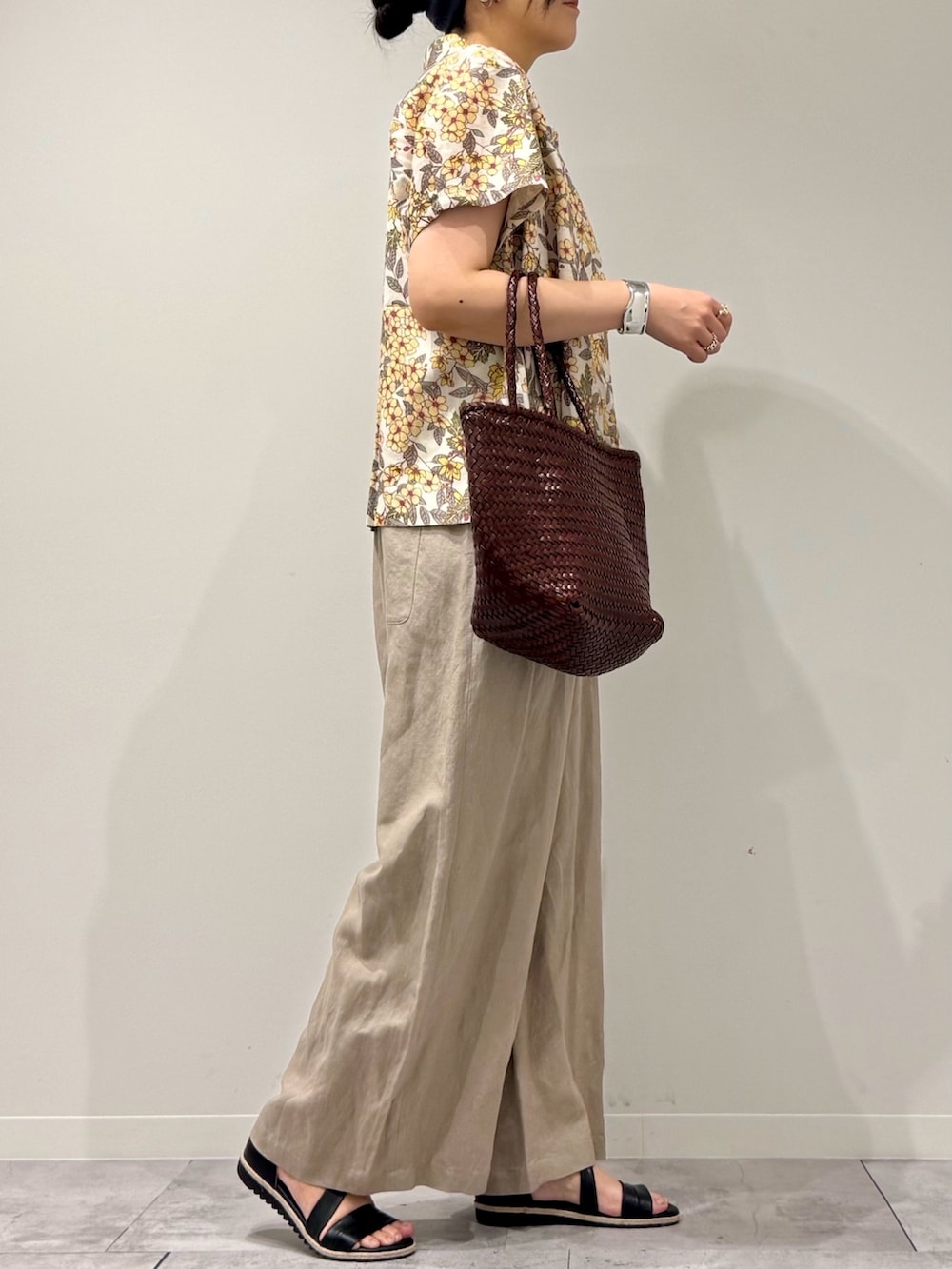 ブラウン系のトートバッグ、ベージュ系のサロペット/オーバーオール、ブラック系のサンダルを着用したレディースの春コーディネートの2枚目の写真