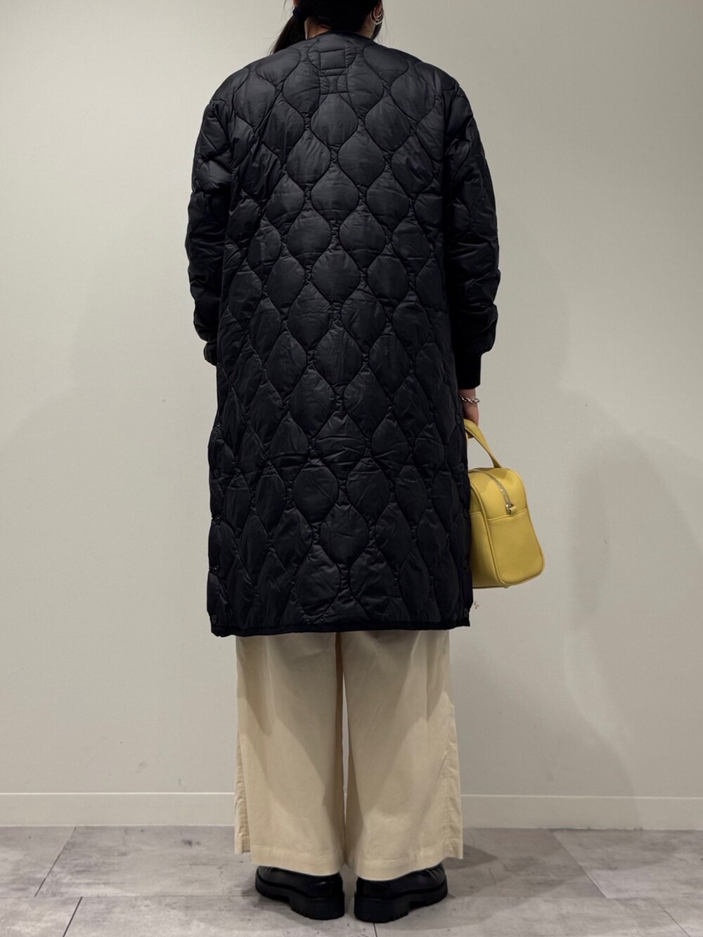 イエロー系のボストンバッグ、ブラウン系のベスト、ホワイト系のその他パンツを着用したレディースの秋コーディネートの3枚目の写真