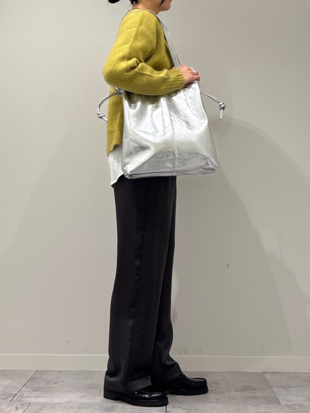 シルバー系のトートバッグ、イエロー系のニット/セーター、ホワイト系のTシャツ/カットソーを着用したレディースの冬コーディネートの2枚目の写真