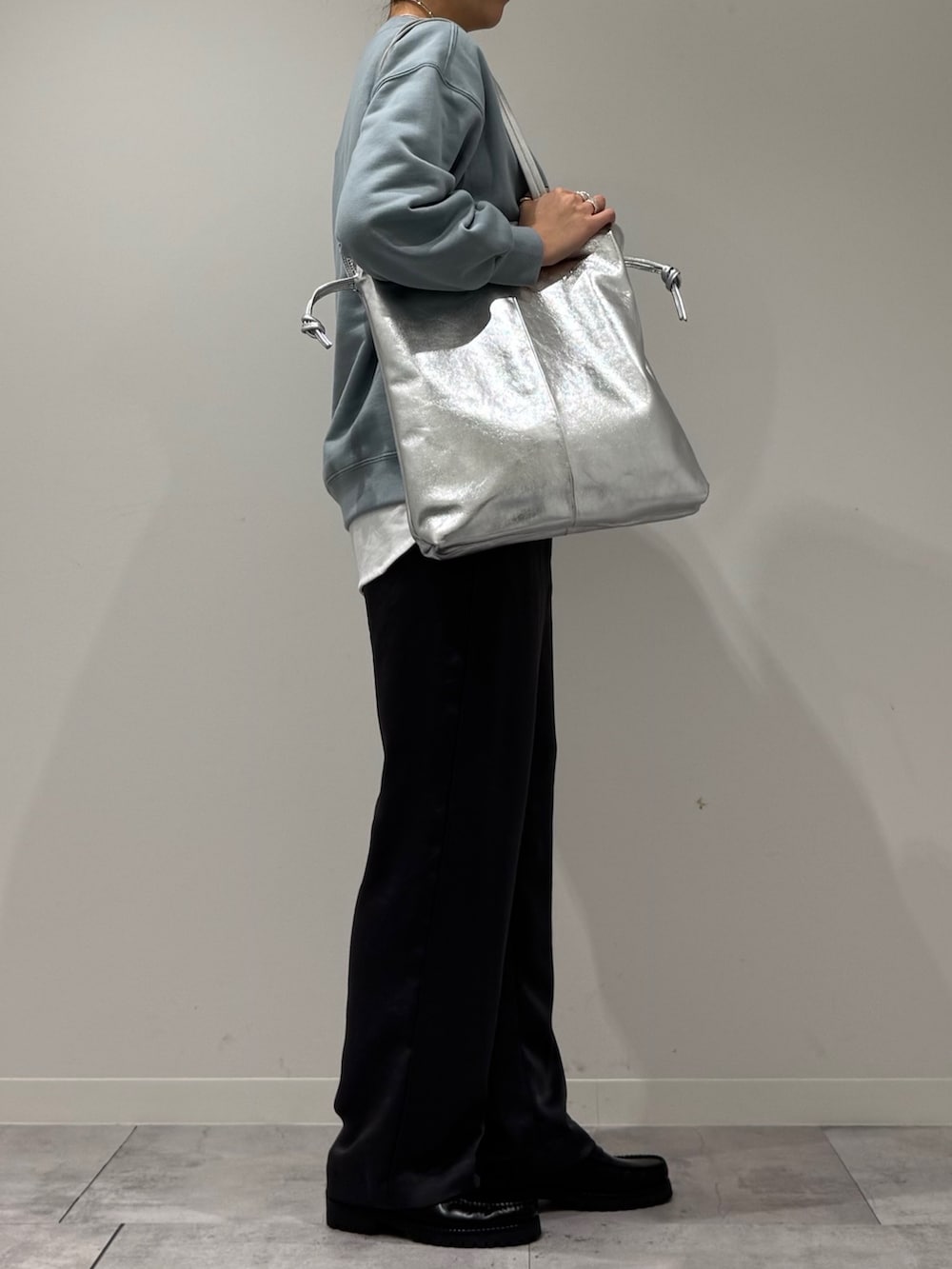 シルバー系のトートバッグ、ブルー系のスウェット、ホワイト系のTシャツ/カットソーを着用したレディースの冬コーディネートの2枚目の写真