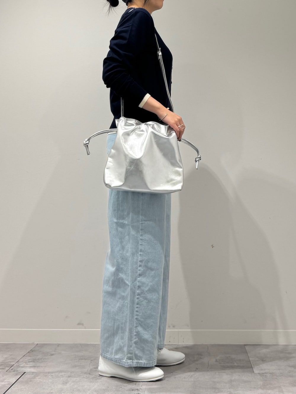 シルバー系のショルダーバッグ、ブルー系のデニムパンツ、ブルー系のカーディガン/ボレロを着用したレディースの春コーディネートの2枚目の写真