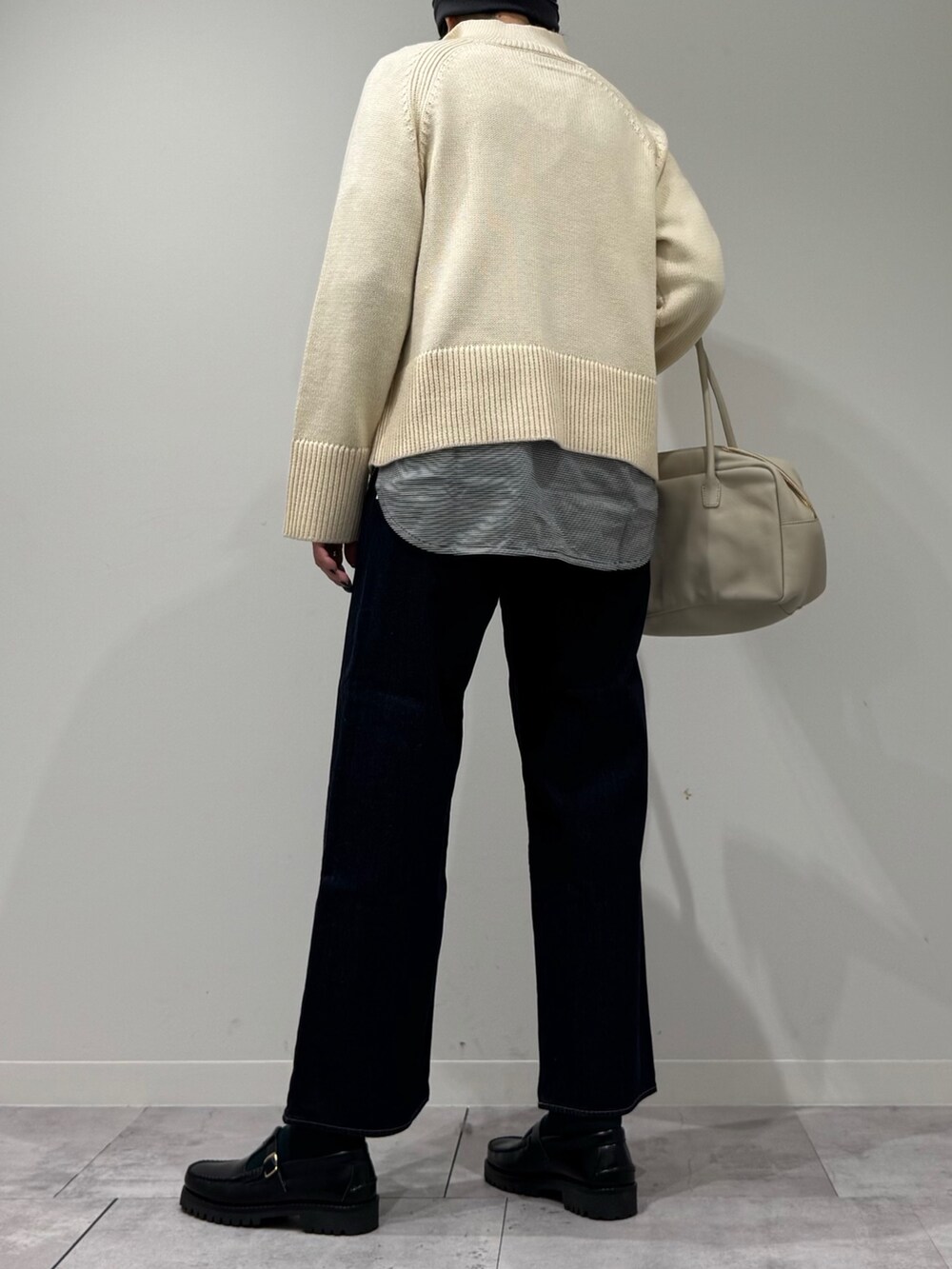 ベージュ系のボストンバッグ、ブルー系のデニムパンツ、ブラック系のローファーを着用したレディースの冬コーディネートの4枚目の写真