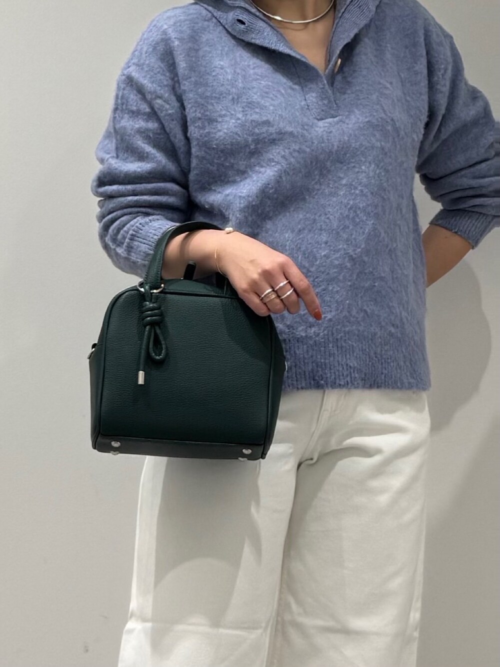 グリーン系のボストンバッグ、ホワイト系のデニムパンツ、ブラック系のローファーを着用したレディースの冬コーディネートの8枚目の写真