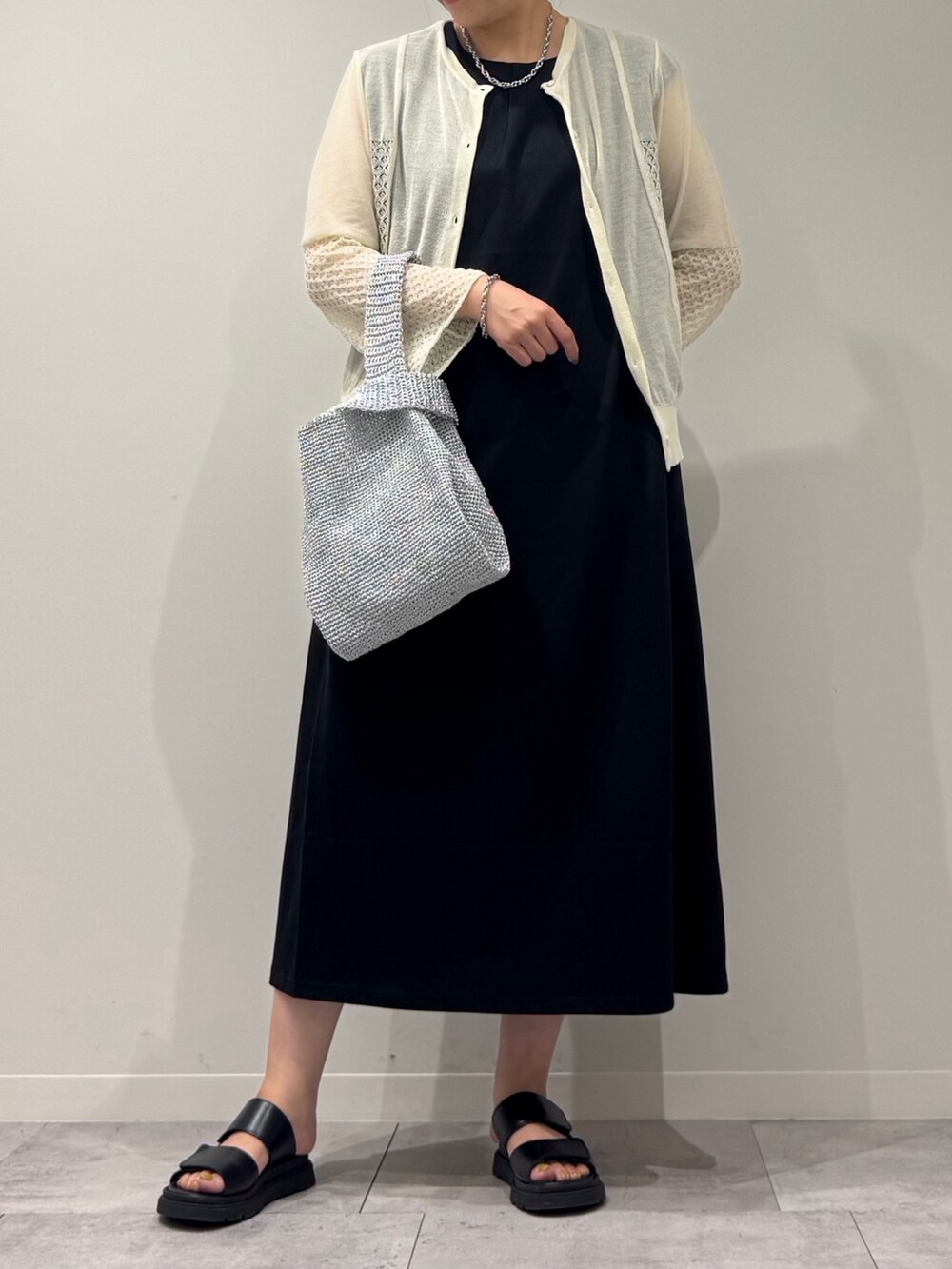 シルバー系のかごバッグ、ブラック系のワンピース、ホワイト系のカーディガン/ボレロを着用したレディースの秋コーディネートの8枚目の写真