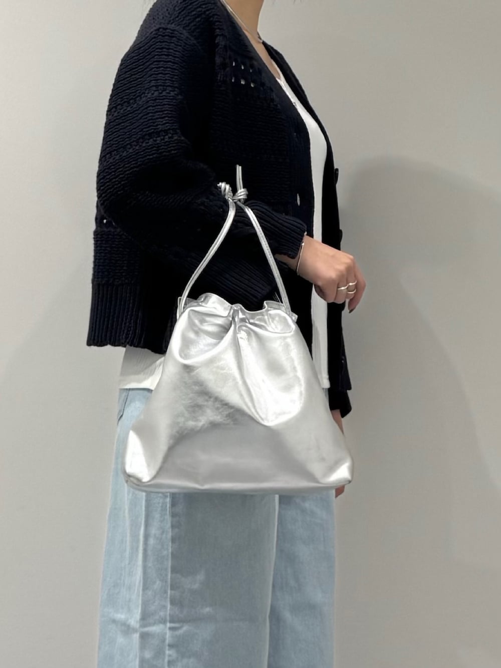 シルバー系のショルダーバッグ、ブルー系のデニムパンツ、ホワイト系のタンクトップを着用したレディースの春コーディネートの8枚目の写真