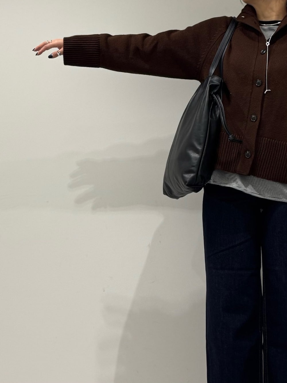 ブラック系のトートバッグ、ブルー系のデニムパンツ、ブラック系のローファーを着用したレディースの冬コーディネートの6枚目の写真