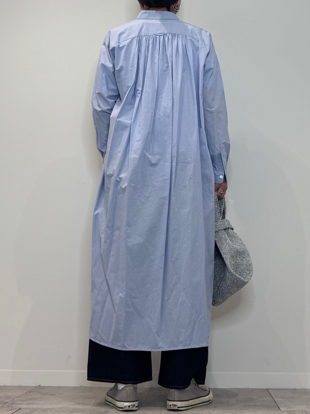 ブルー系のシャツワンピース、シルバー系のかごバッグ、ブルー系のデニムパンツを着用したレディースの春コーディネートの4枚目の写真