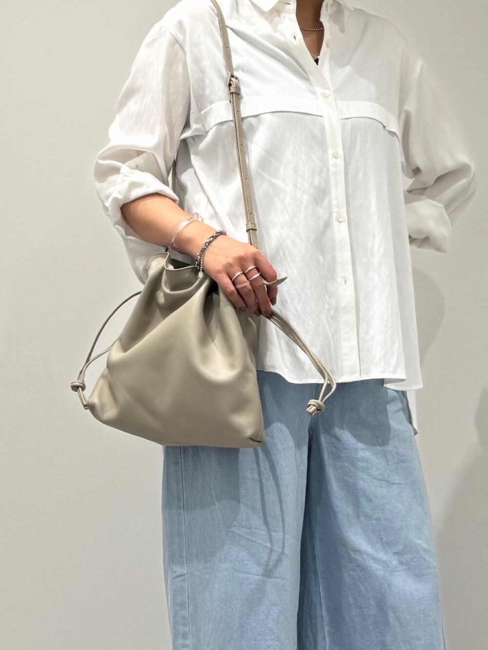 ベージュ系のショルダーバッグ、ブルー系のデニムパンツ、ブラック系のサンダルを着用したレディースの秋コーディネートの9枚目の写真