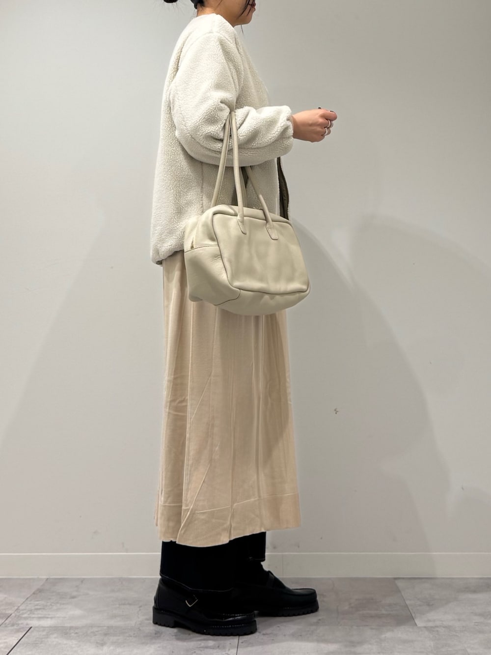 ベージュ系のボストンバッグ、ベージュ系のワンピース、ブルー系のデニムパンツを着用したレディースの春コーディネートの3枚目の写真